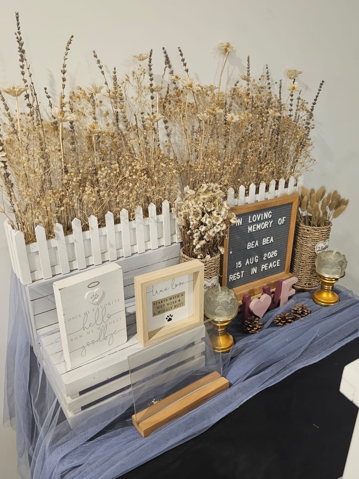 Memorial table with dried flowers, candles and an In Loving Memory letter board